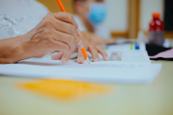 A student writing on paper during a lesson, reflecting the test scores measured in the WestEd study of Nevada at-risk funding