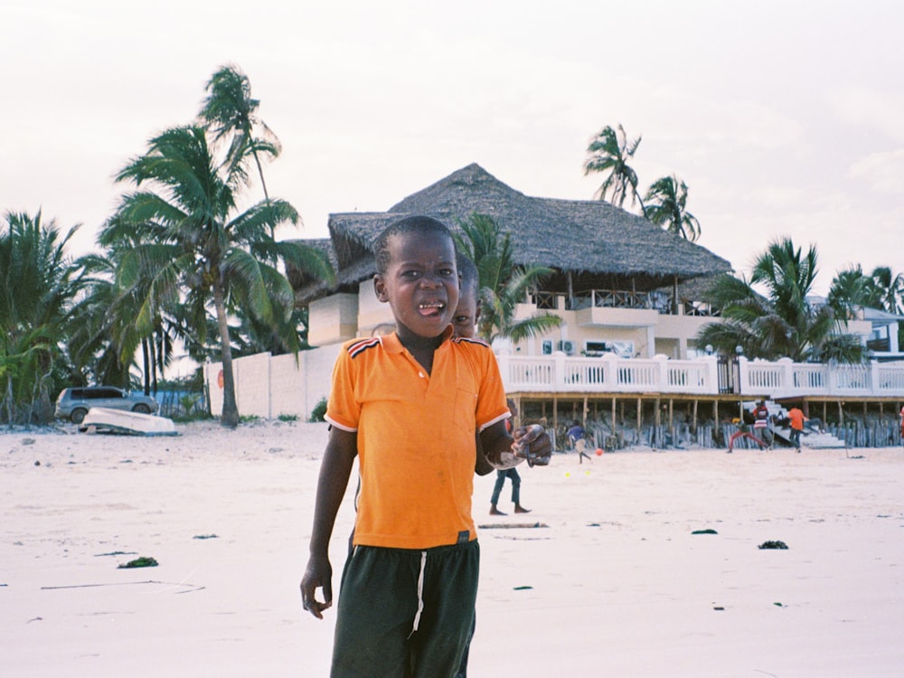 man in orange polo shirt standing on white sand during daytime