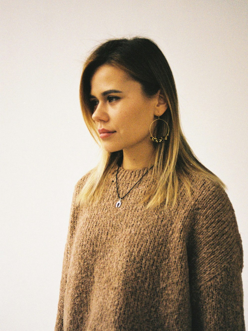 woman in brown knit sweater wearing silver necklace