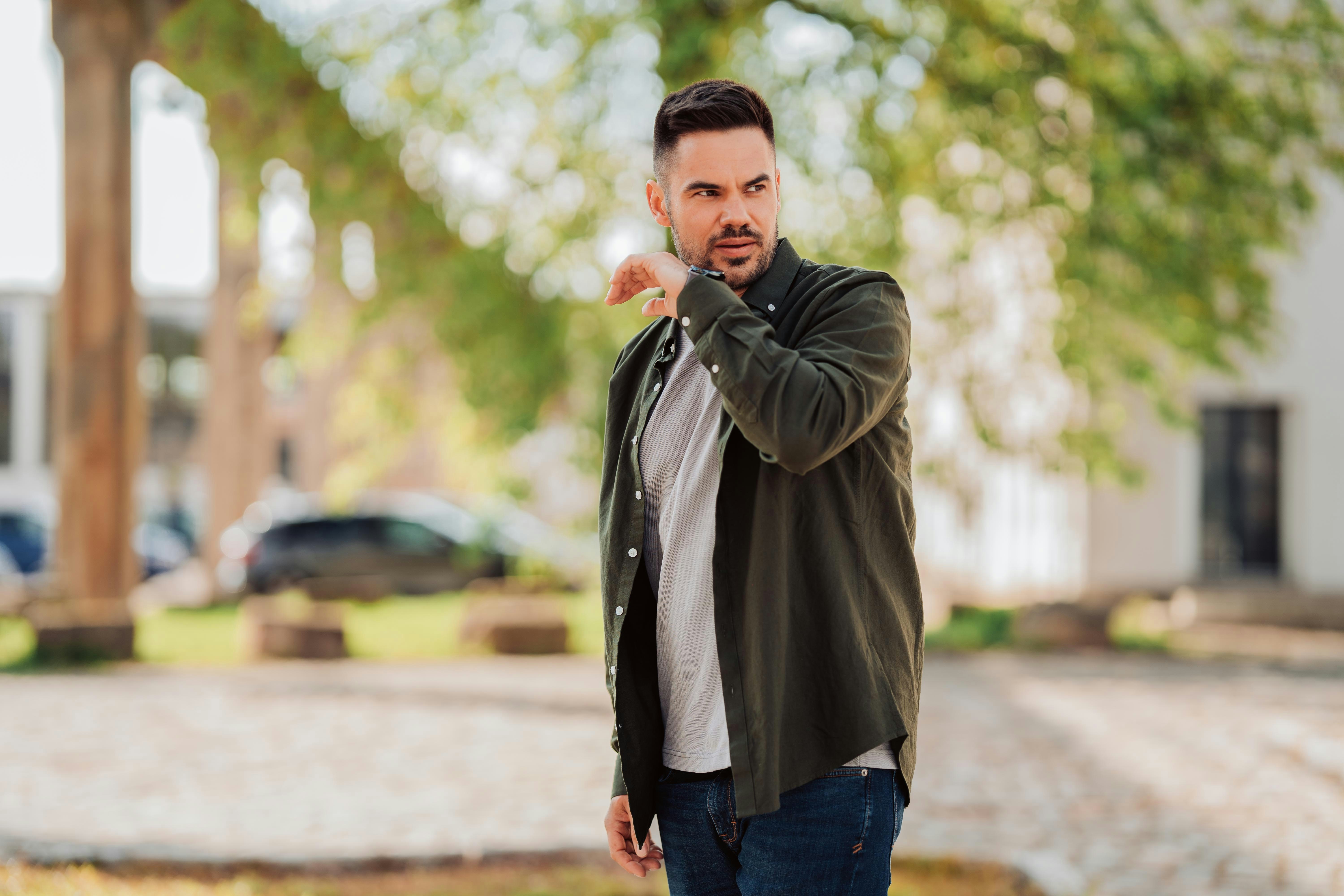 man in black leather jacket standing on road during daytime