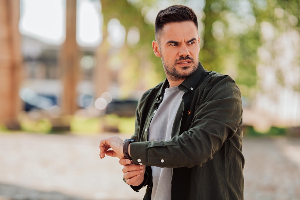 man in black zip up jacket holding black smartphone