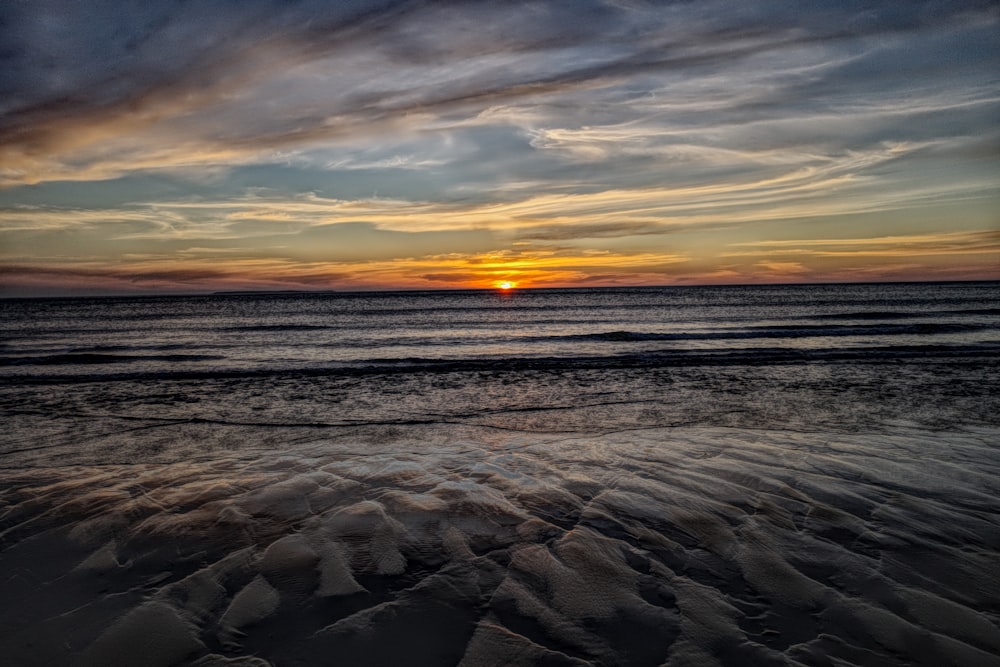 sea waves crashing on shore during sunset