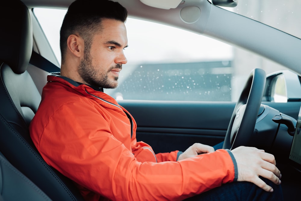 man in red jacket driving car