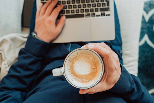person holding white ceramic mug with brown liquid