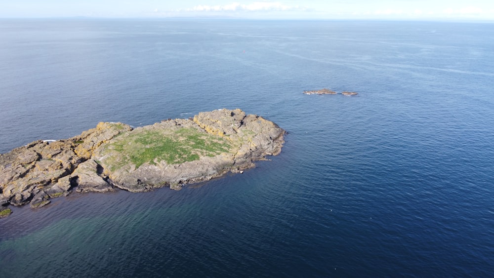 aerial view of green and brown rock formation on sea during daytime