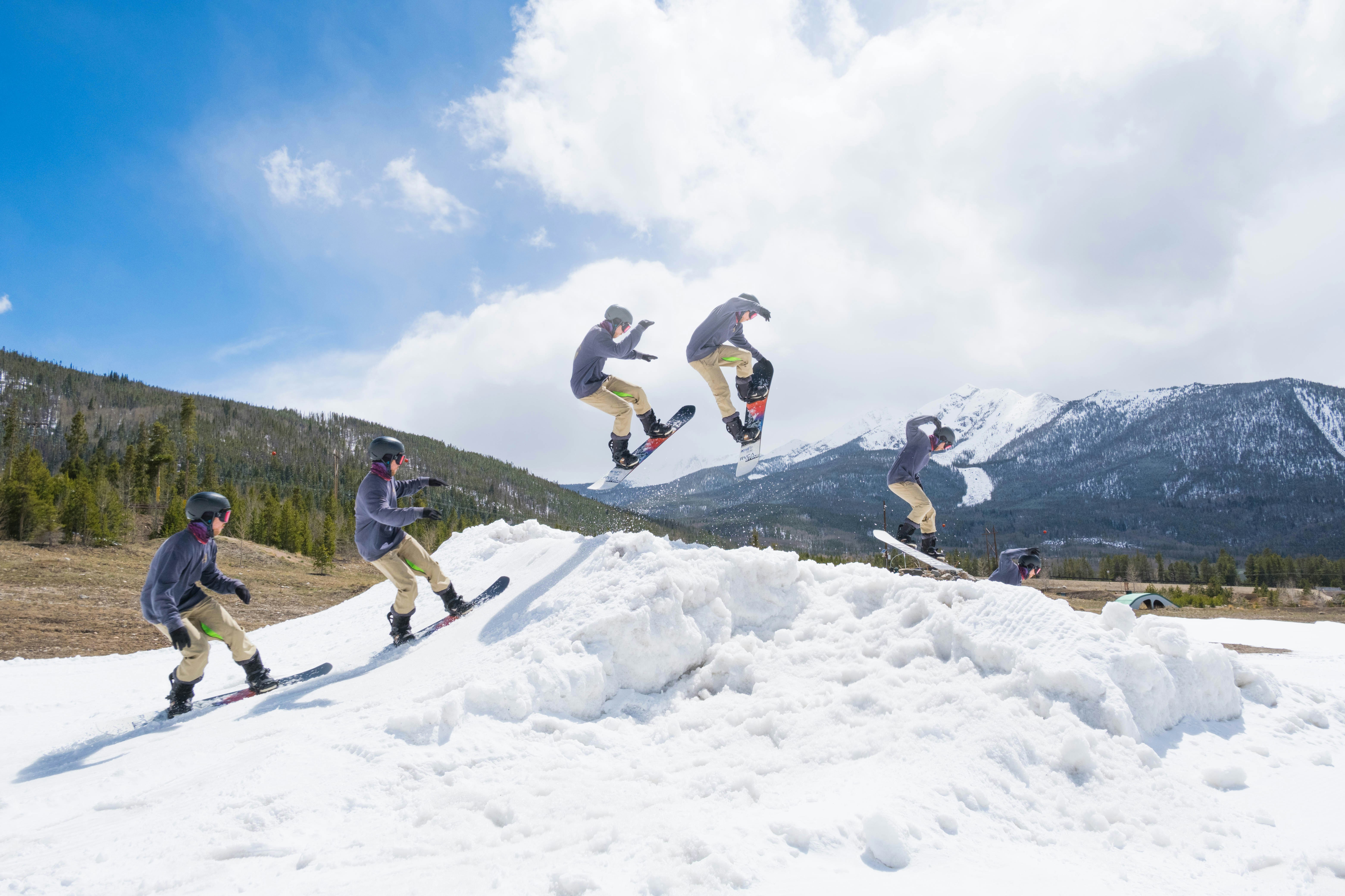 2 men jumping on snow covered mountain during daytime