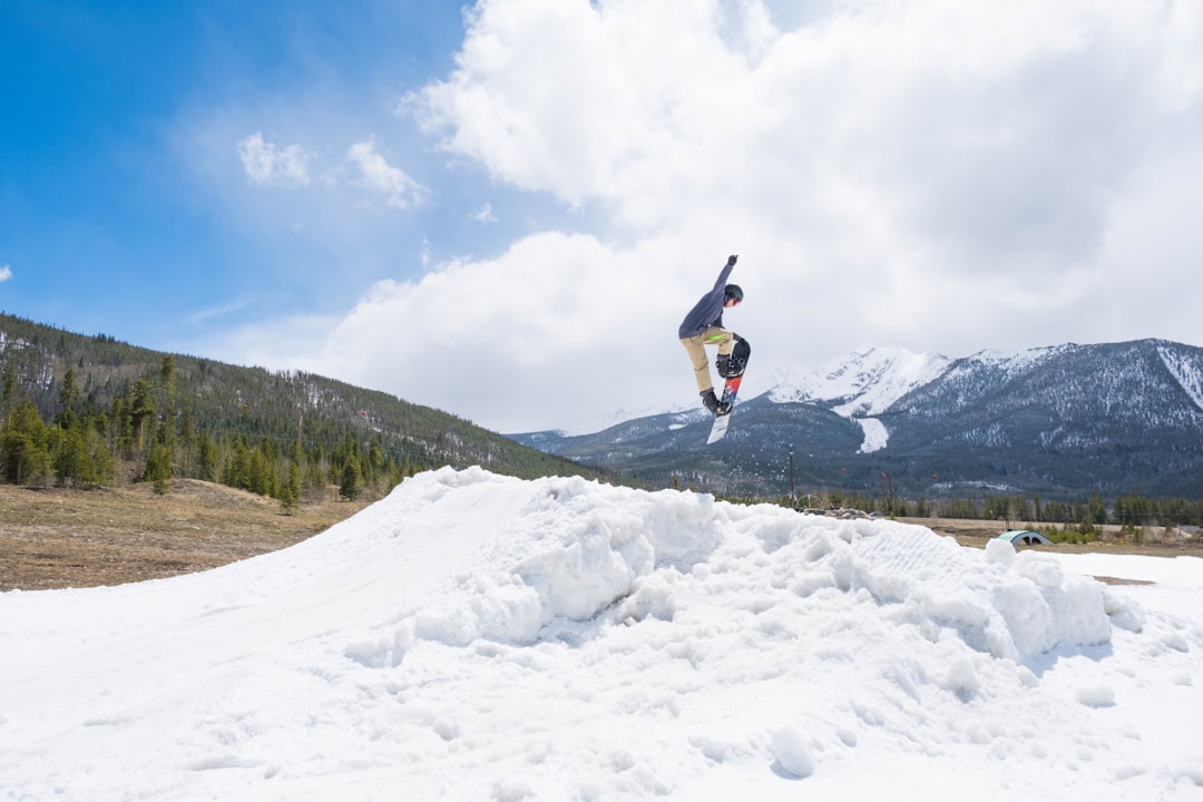 person in black jacket and blue denim jeans jumping on snow covered ground during daytime