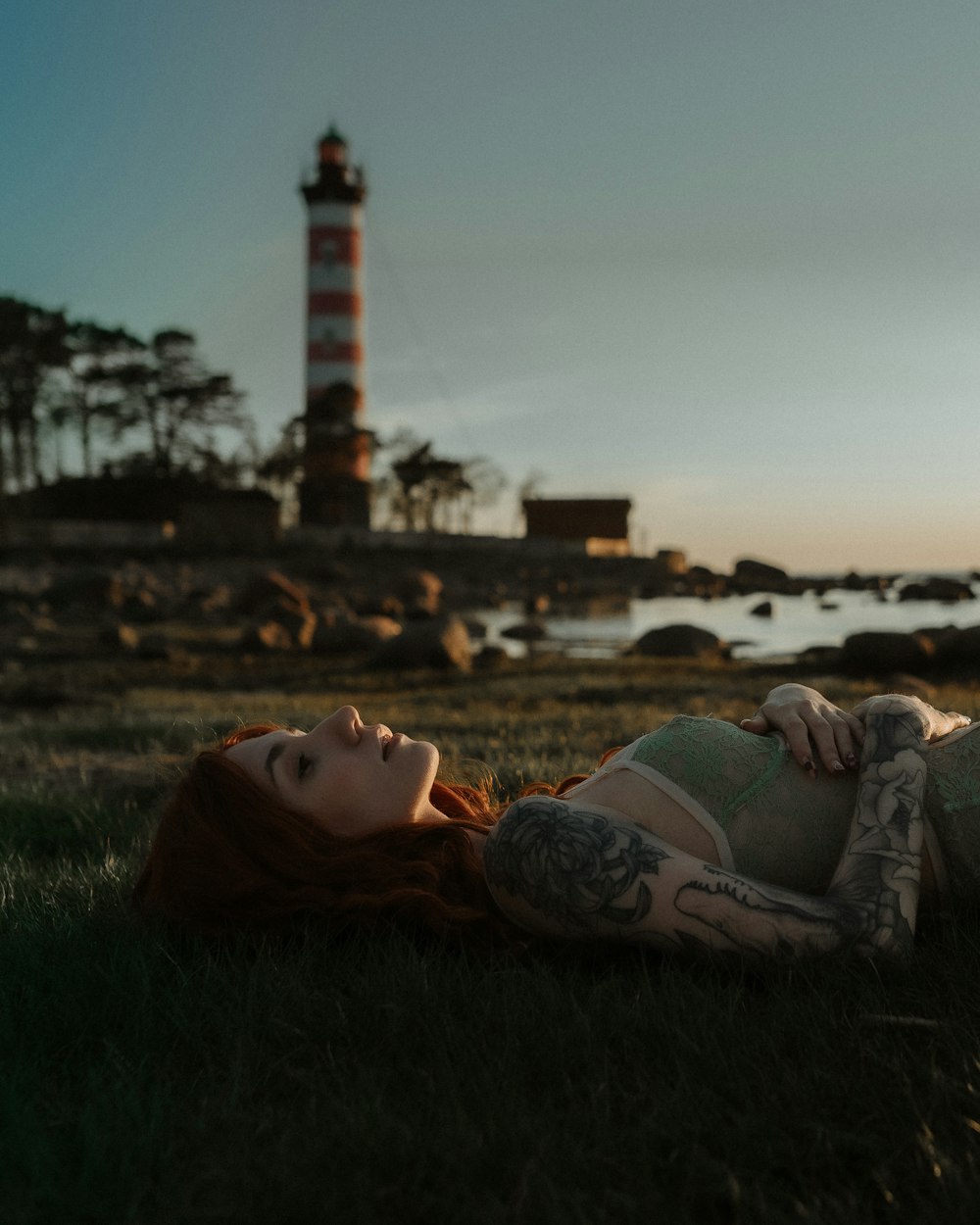 woman in gray brassiere lying on green grass field during daytime