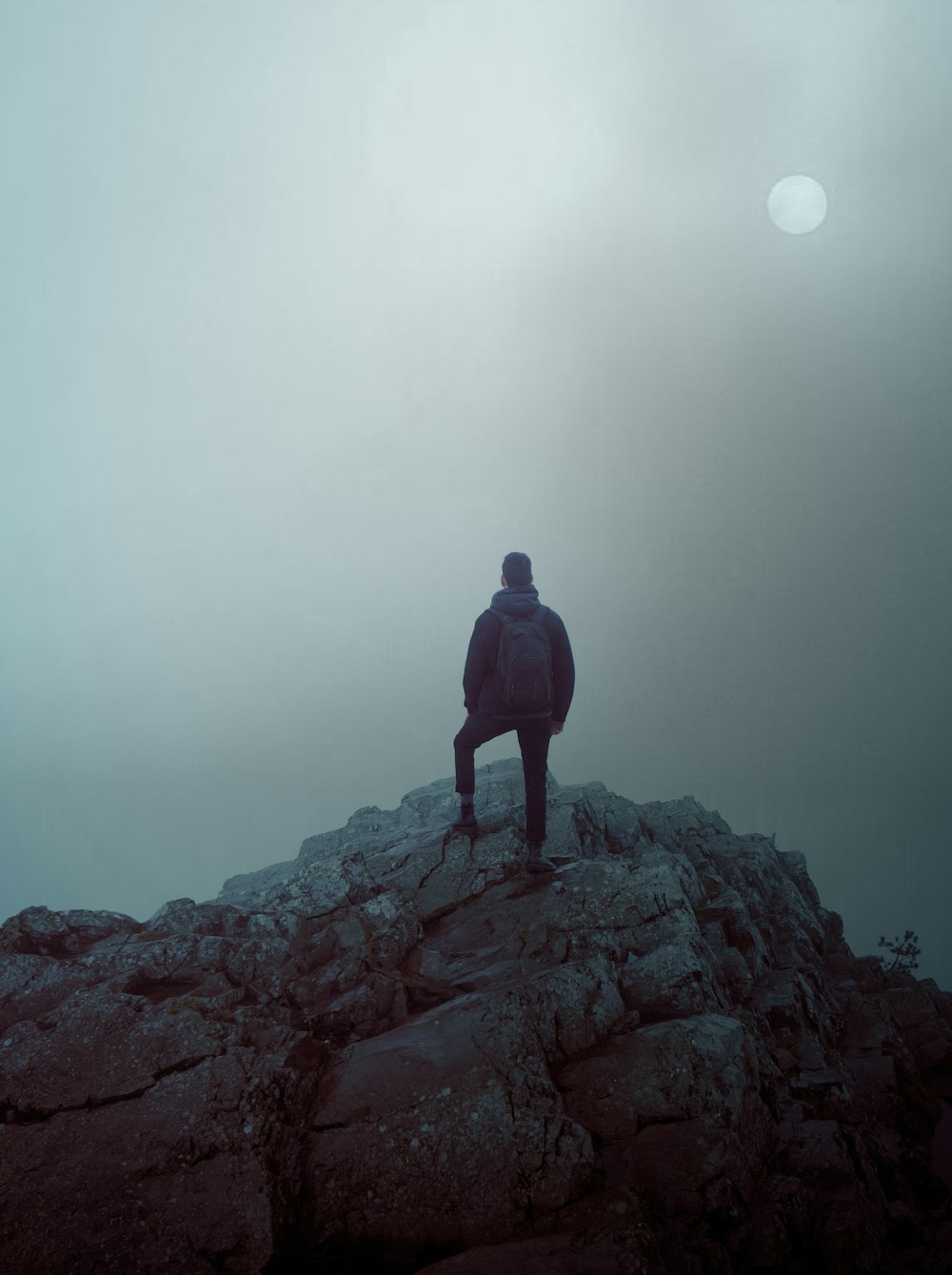 man in black jacket standing on rock formation during daytime