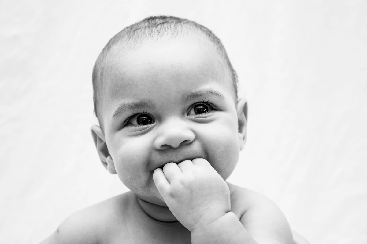 Baby with hand in mouth, a classic sign of teething discomfort