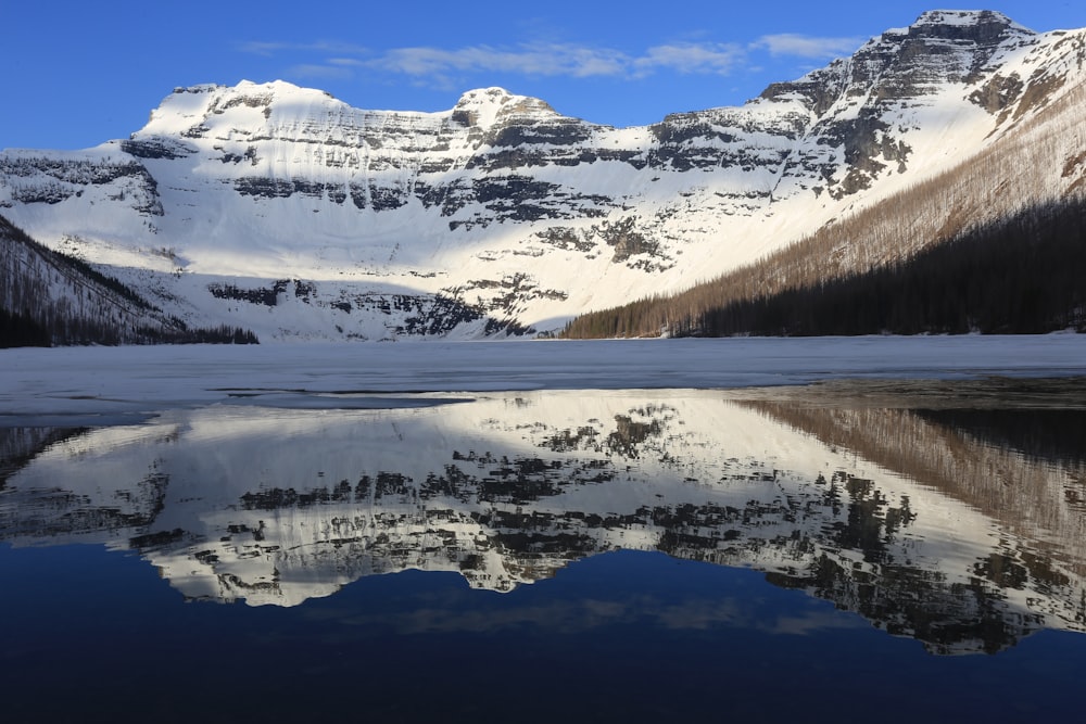 snow covered mountain near lake during daytime