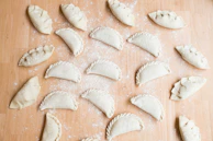 A warm kitchen scene with hands folding empanadas, surrounded by fresh ingredients like onions, peppers, and meat.