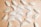 Multiple uncooked empanadas are arranged on a floured wooden surface. Each empanada is folded and sealed in a variety of styles, with some having intricate braided edges and others simple, rounded edges. The background is lightly dusted with flour, adding to the preparation theme.