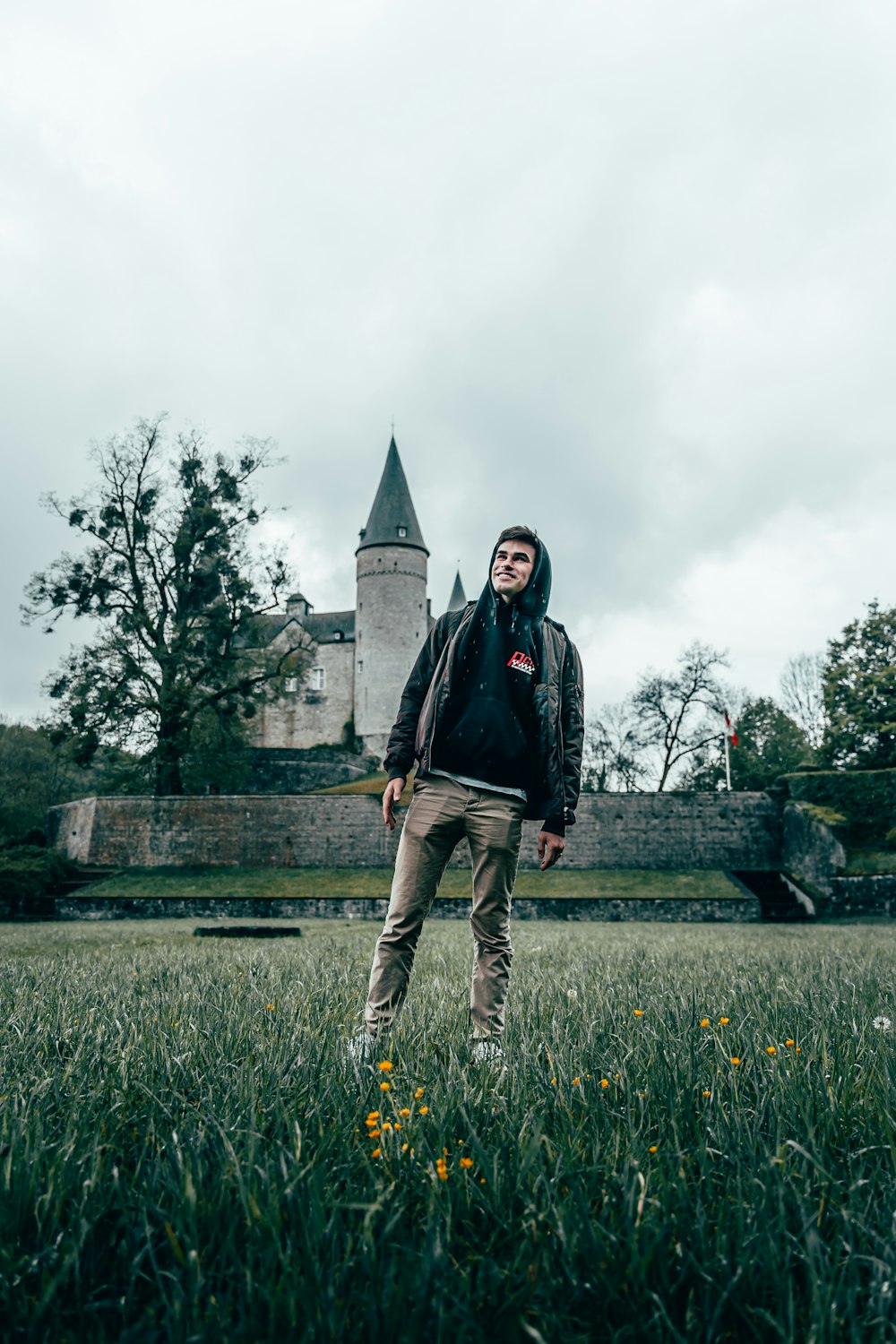 man in black jacket standing on green grass field near pyramid during daytime