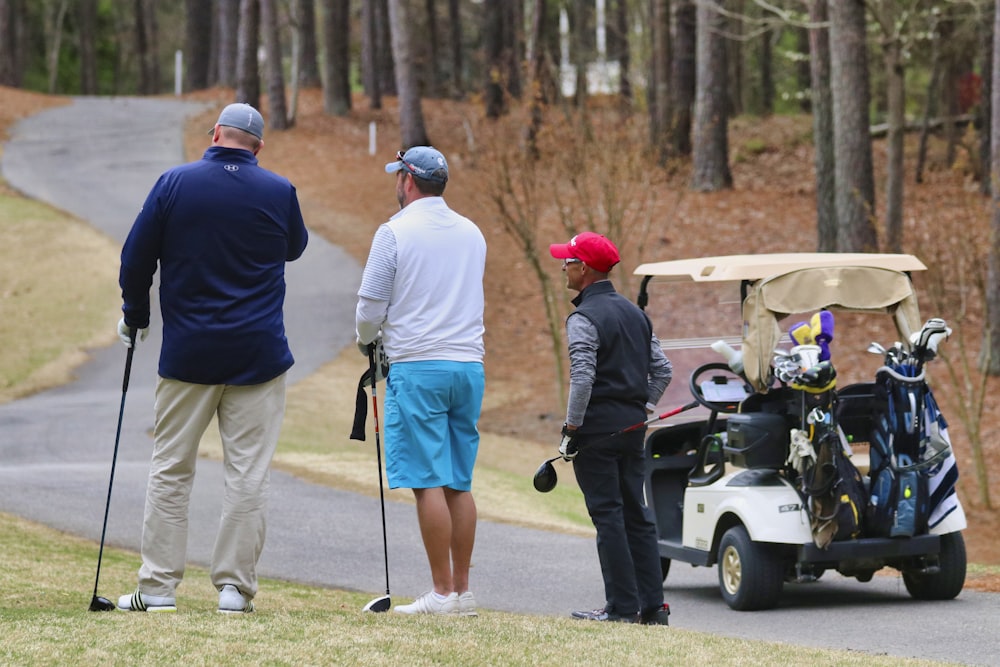 3 men in white uniform riding golf cart during daytime