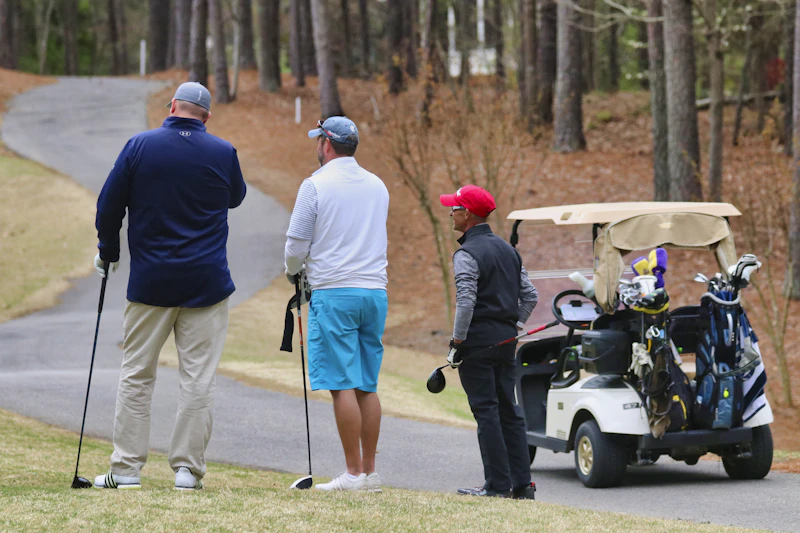Group of golfers with their bags by a golf cart