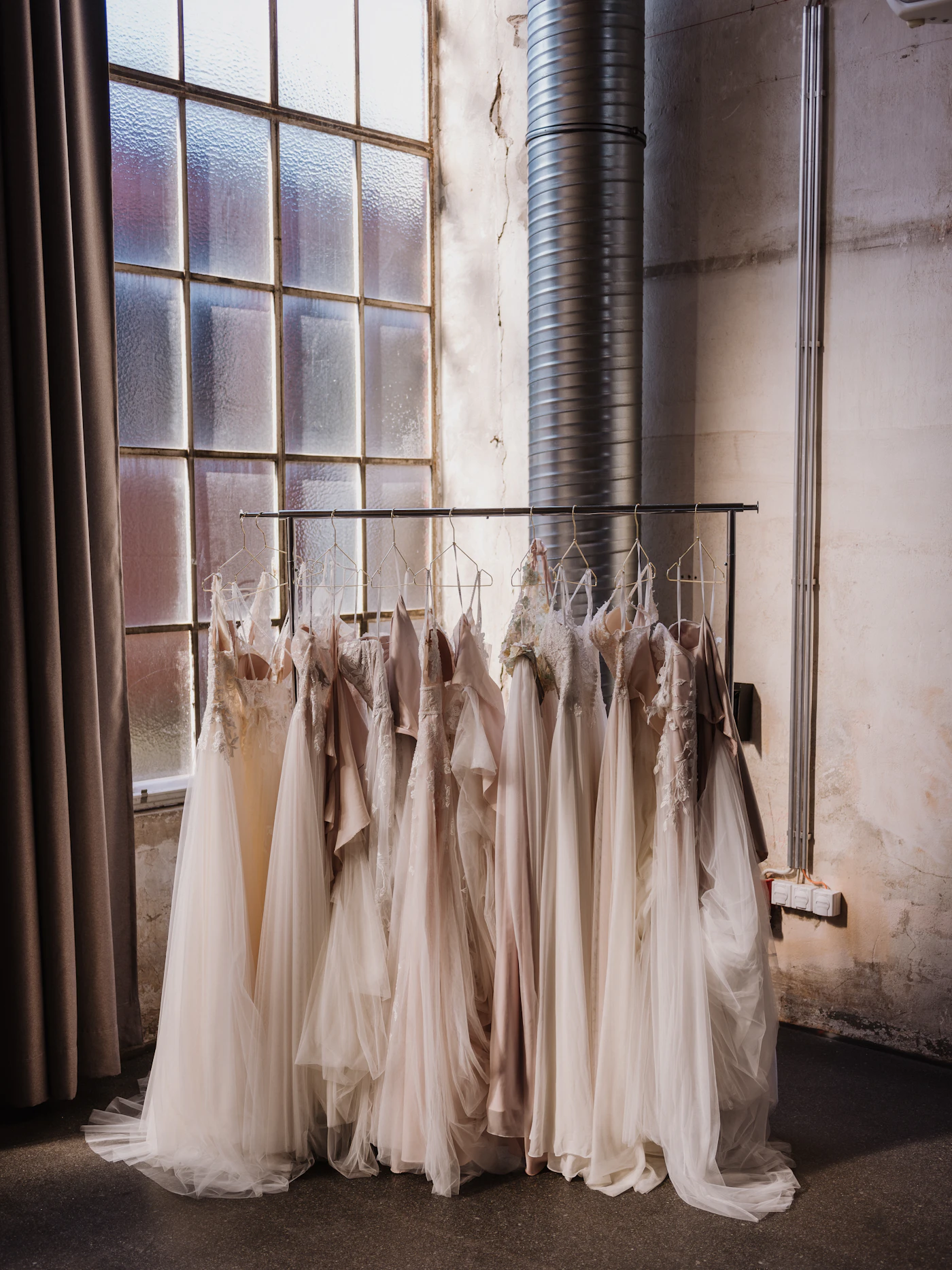 Affordable replica wedding dresses from Instagram brands — Multiple white wedding dresses hang on a rack in a bright bridal shop.