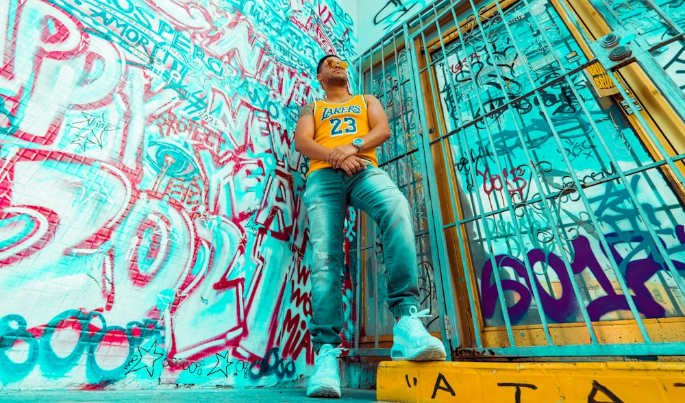 man in blue denim jeans sitting on yellow and black metal fence