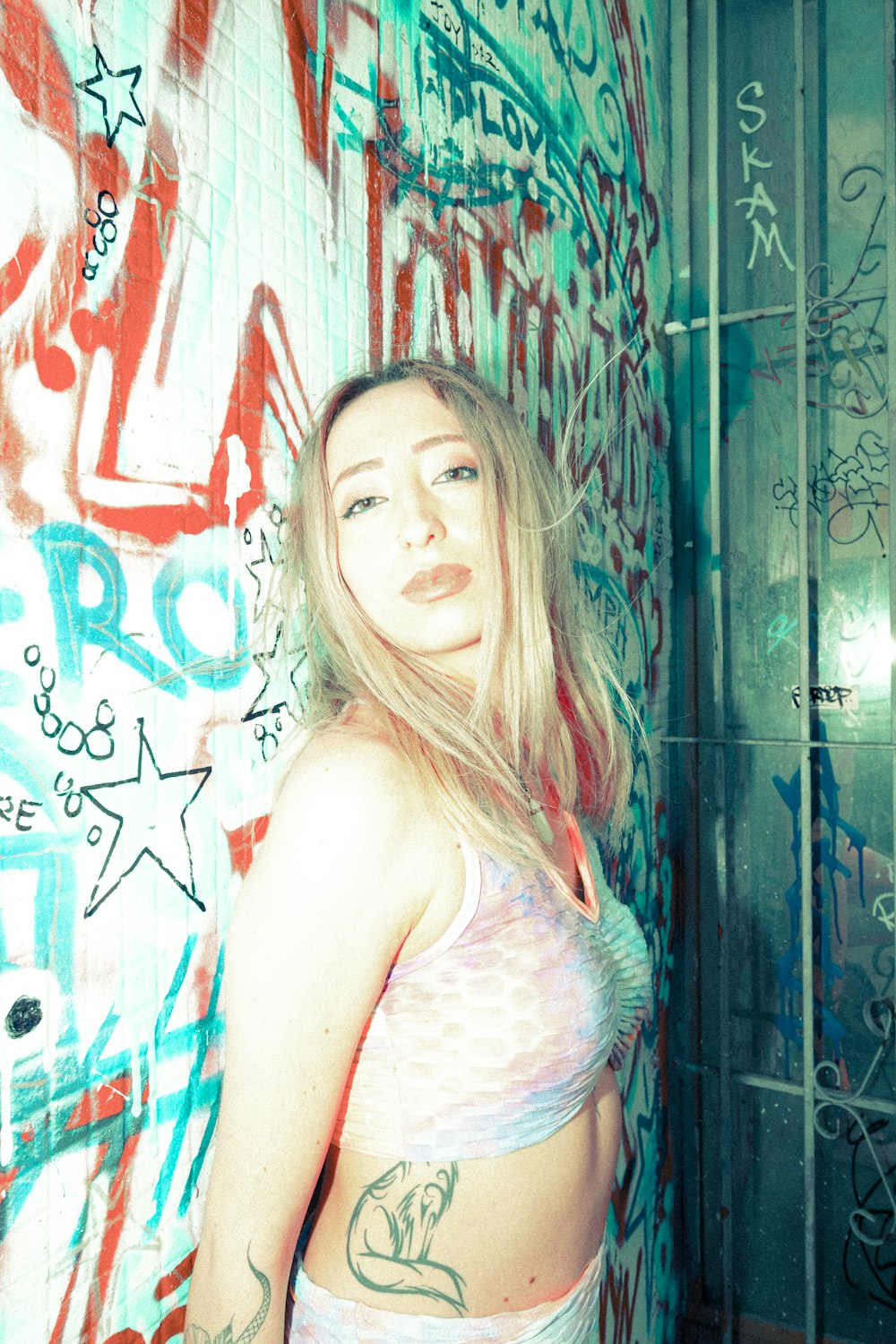 woman in white tank top leaning on wall