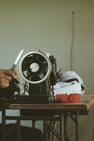 Hands adjusting the settings on a well-maintained sewing machine ready for stitching.