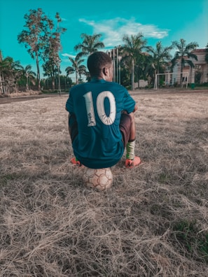 man in blue and white crew neck t-shirt and red shorts standing on green grass