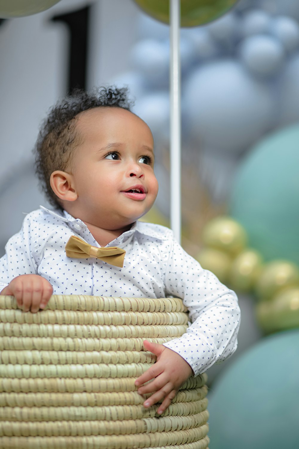 baby in white and yellow polka dot long sleeve shirt sitting on brown woven chair