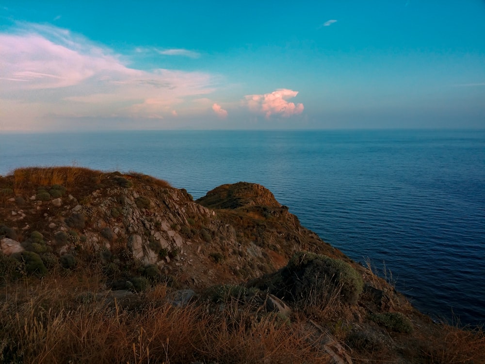 brown rock formation beside blue sea under blue sky during daytime