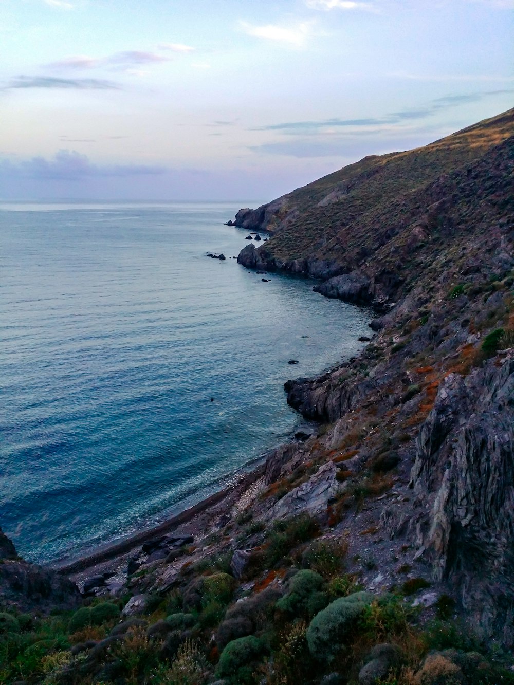 green and brown mountain beside sea during daytime