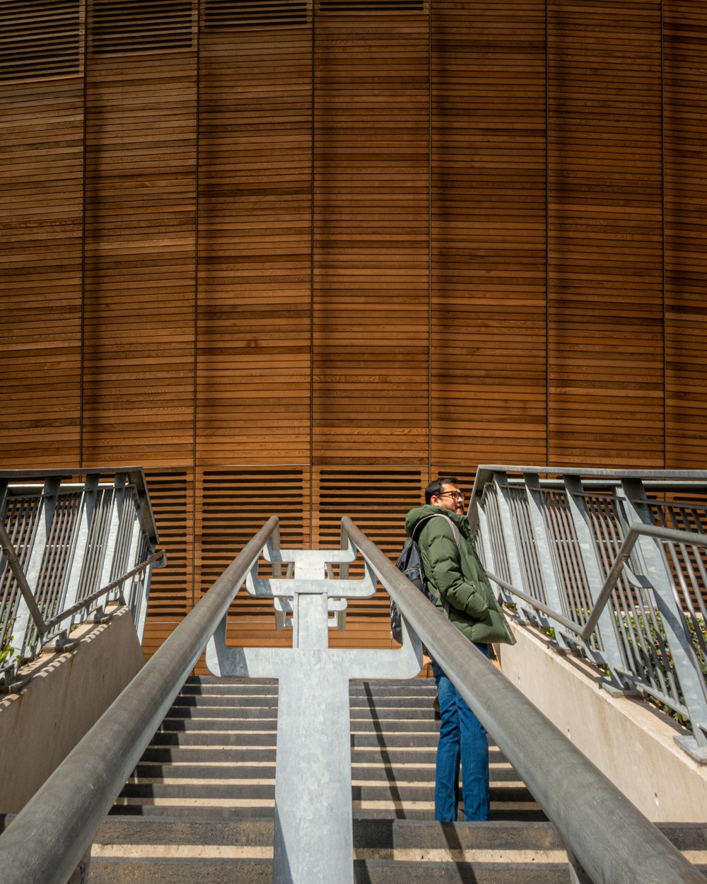 man in green jacket and blue denim jeans walking down the stairs