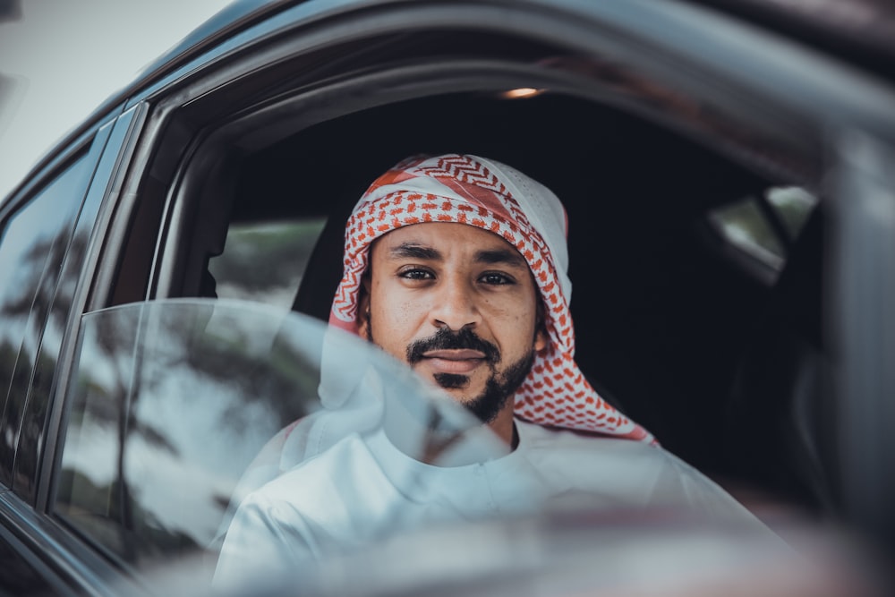 man in white long sleeve shirt wearing red and white hijab inside car