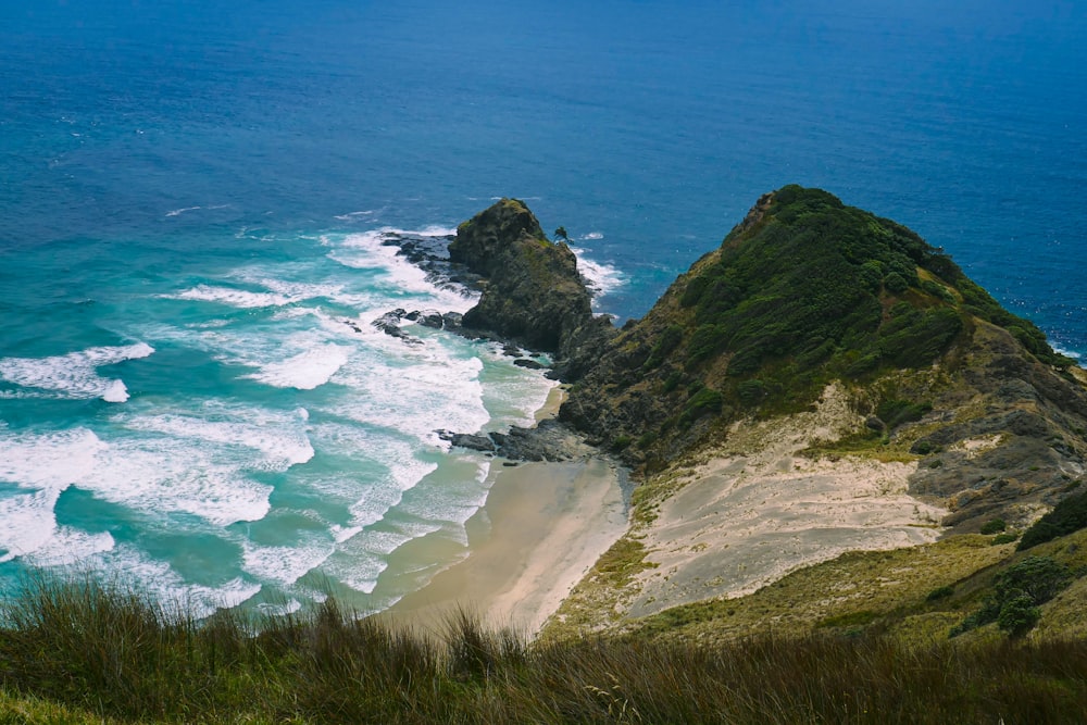 green and brown mountain beside blue sea during daytime