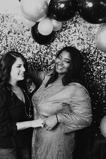 2 femmes souriant en se prenant en photo devant un photobooth loué pendant un anniversai