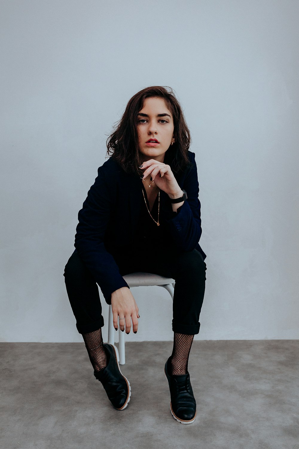 woman in black long sleeve shirt and black pants sitting on white chair