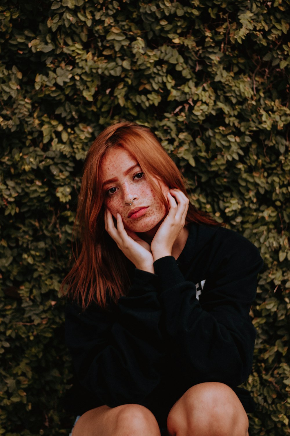 woman in black jacket near green leaves