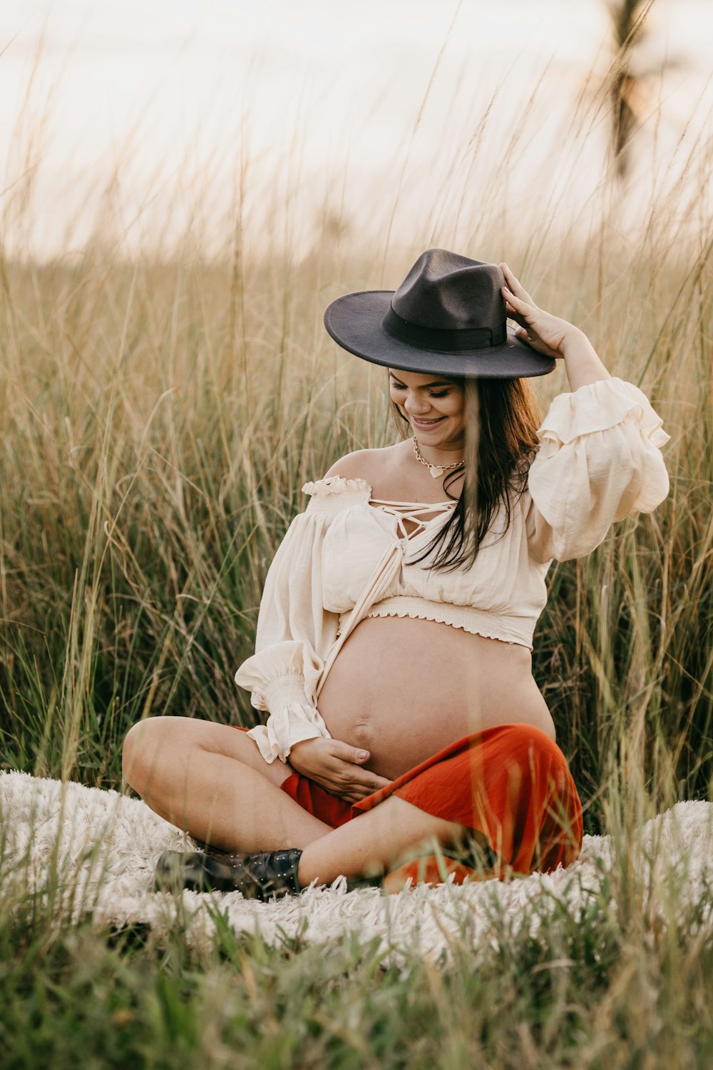 woman in white long sleeve shirt and red skirt sitting on white textile