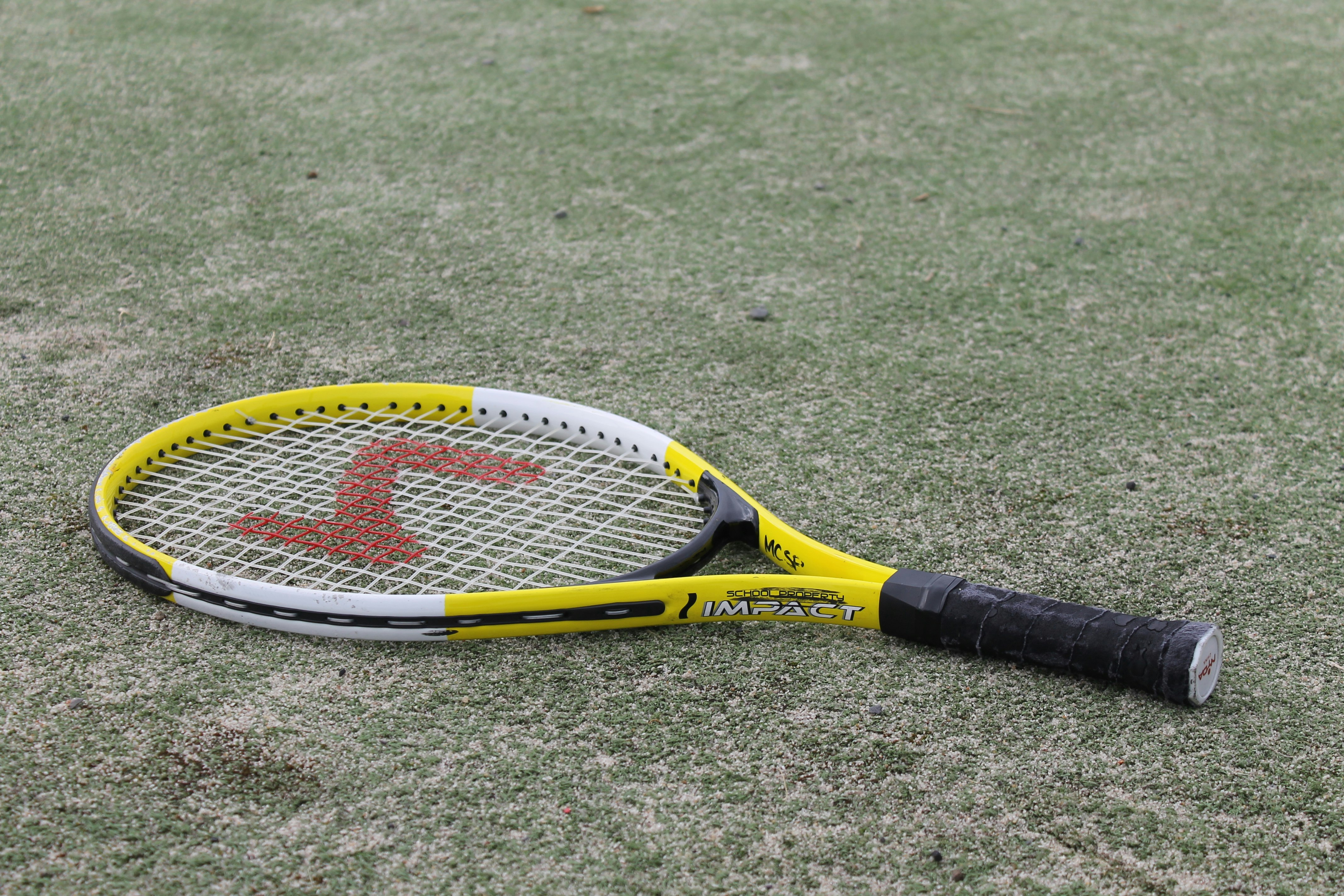 yellow and black tennis racket on green grass field