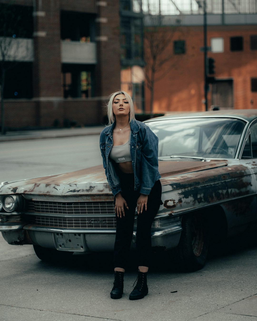 woman in blue denim jacket standing beside black mercedes benz coupe during daytime