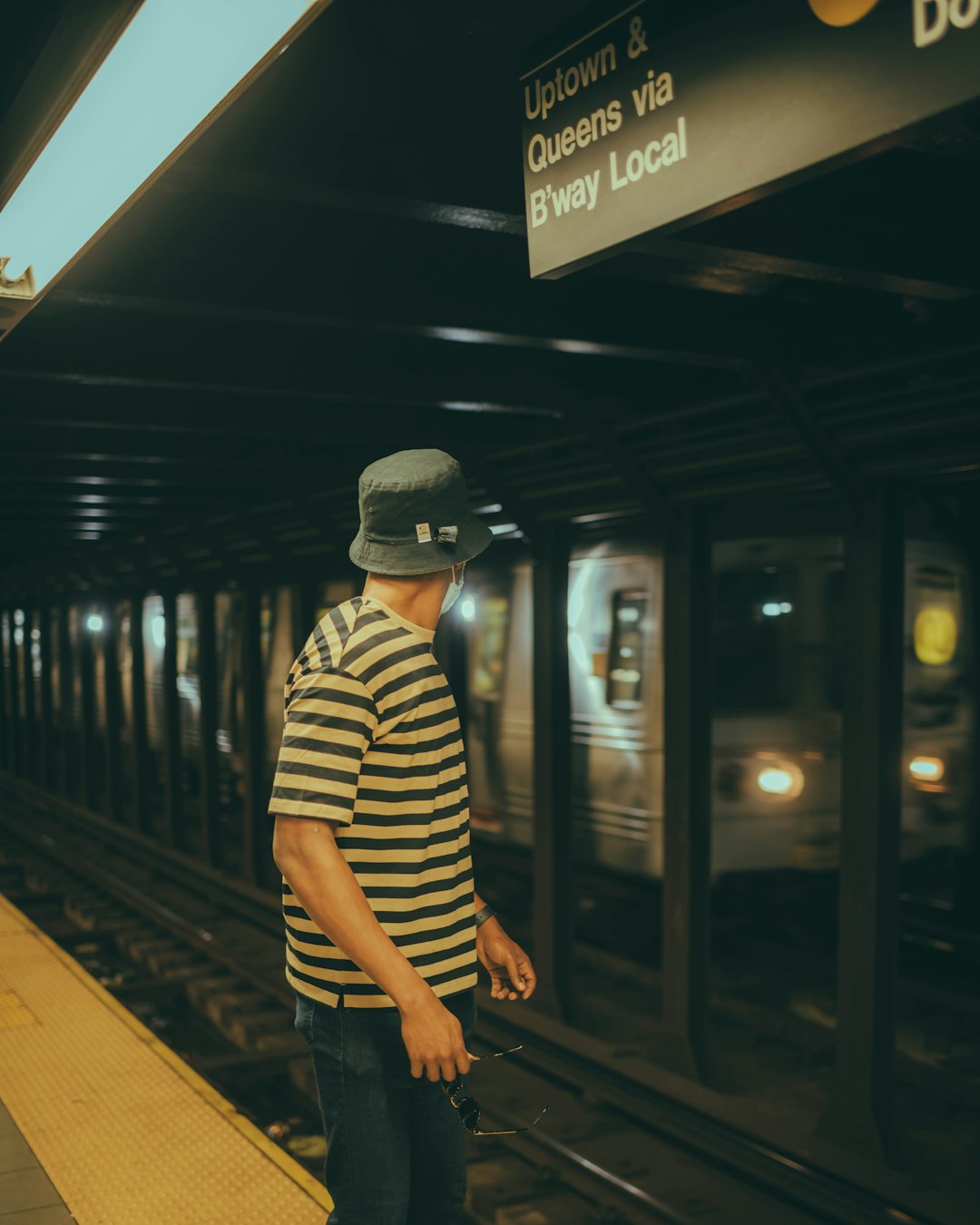 man in black and white striped long sleeve shirt standing on train station