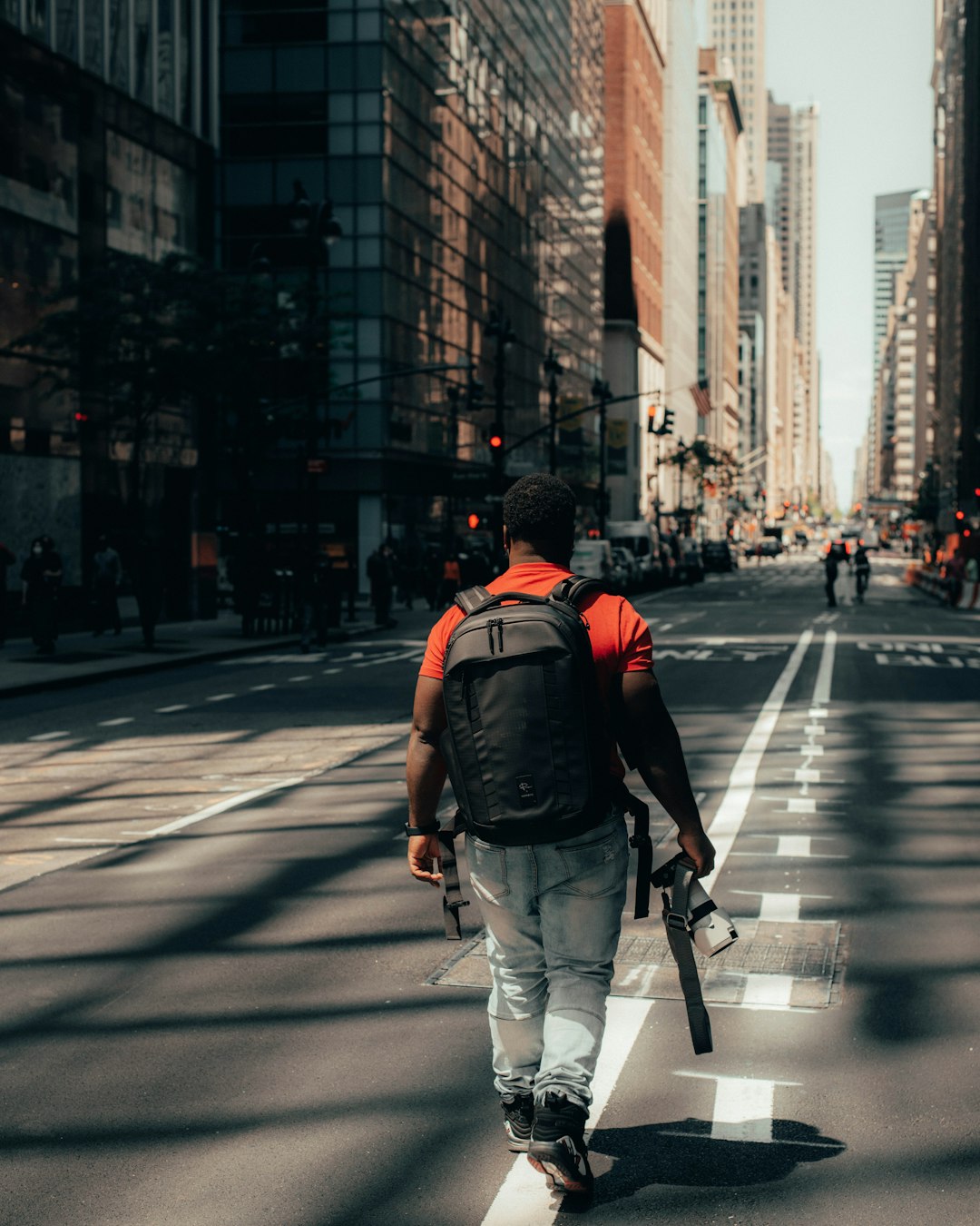 man in red backpack walking on pedestrian lane during daytime