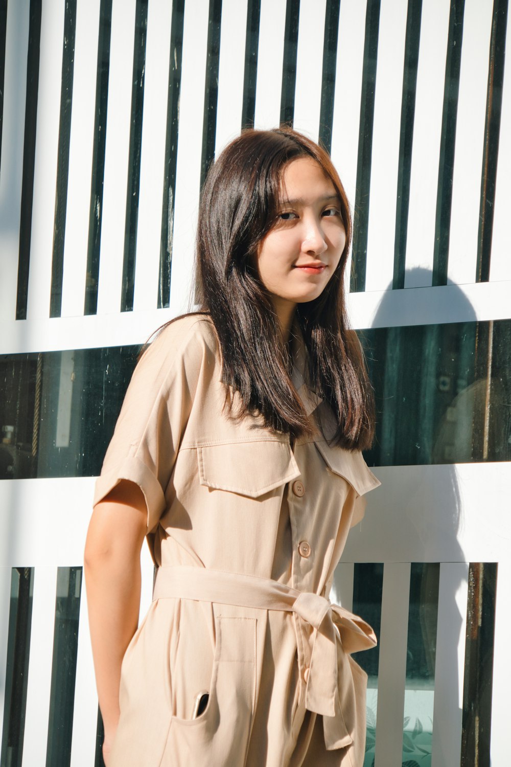 woman in brown dress standing near white wooden fence