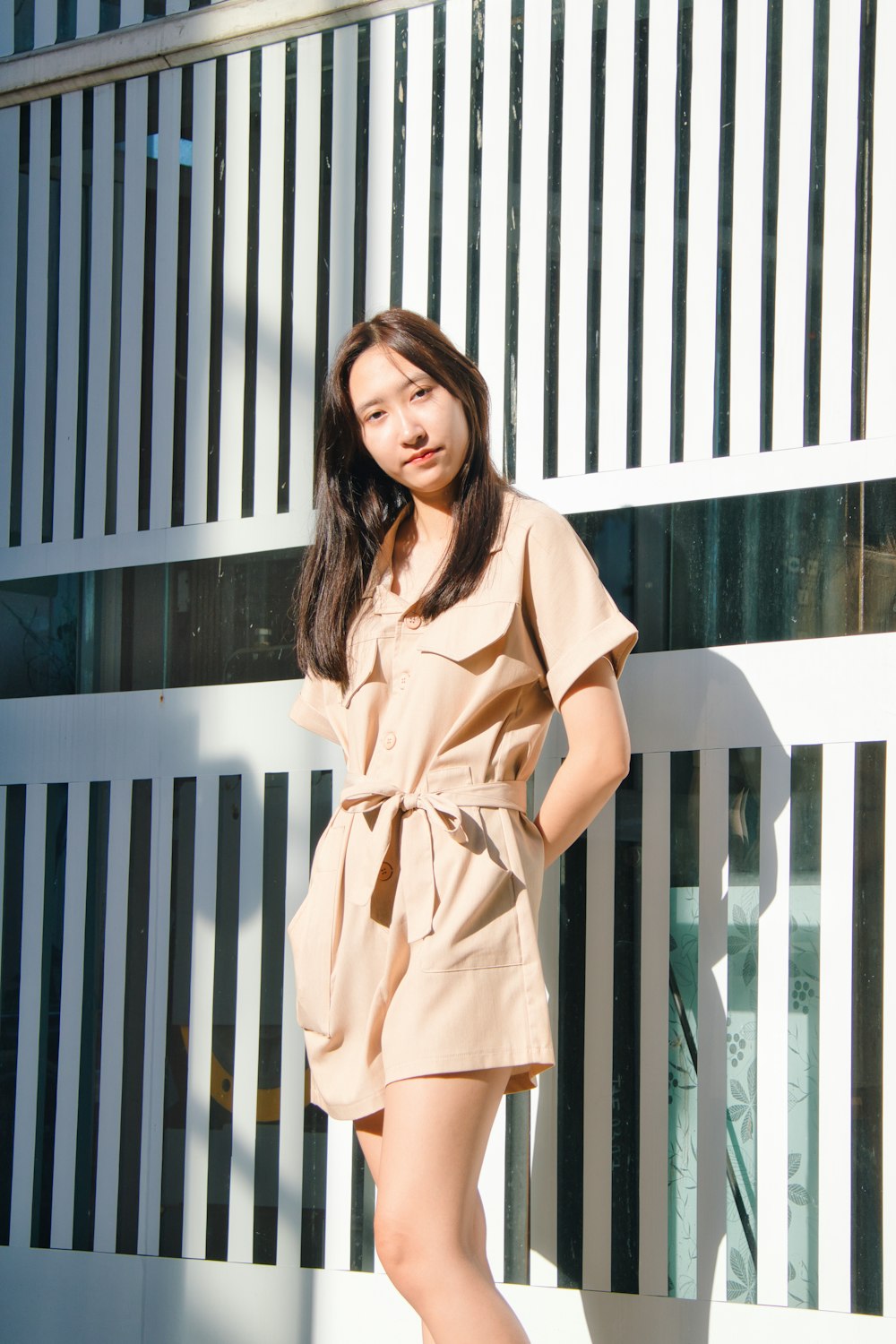 woman in brown dress standing near white wooden fence