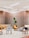 A modern interior space with wooden slat walls and ceiling lighting. The room features a variety of seating options including patterned and solid-colored chairs, a beige couch, and contemporary furniture with geometric designs. A large potted plant adds a touch of greenery to the setting.