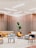 A modern interior space with wooden slat walls and ceiling lighting. The room features a variety of seating options including patterned and solid-colored chairs, a beige couch, and contemporary furniture with geometric designs. A large potted plant adds a touch of greenery to the setting.