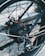 Close-up view of a bicycle's rear wheel and gear system, showing intricate details of the spokes, chain, and mechanical components. The brand name 'Shimano' is visible on the gear assembly.