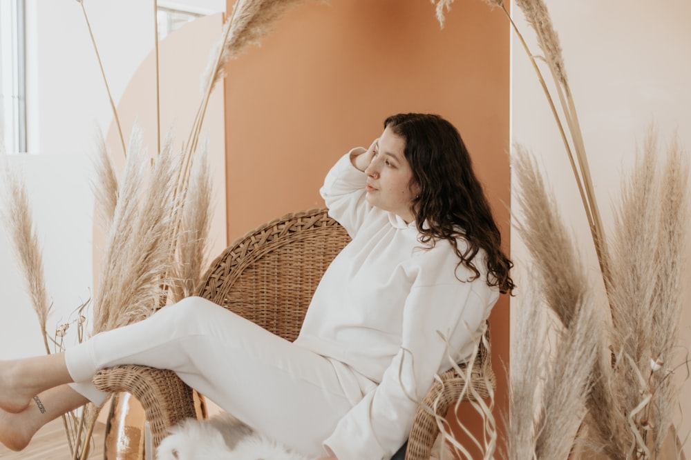 woman in white long sleeve shirt sitting on brown wicker chair