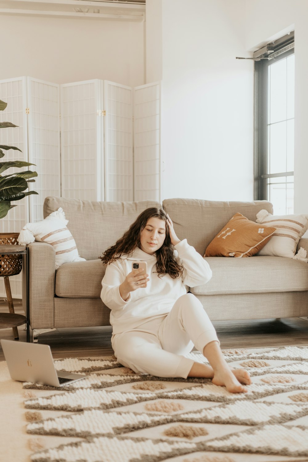 woman in white long sleeve shirt and white pants sitting on brown couch