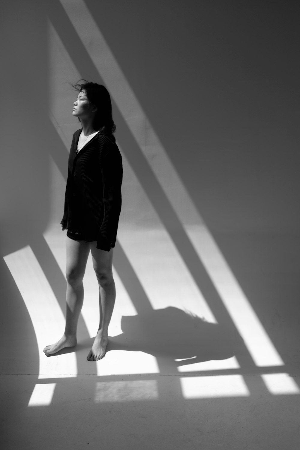 woman in black coat and black skirt standing on white floor