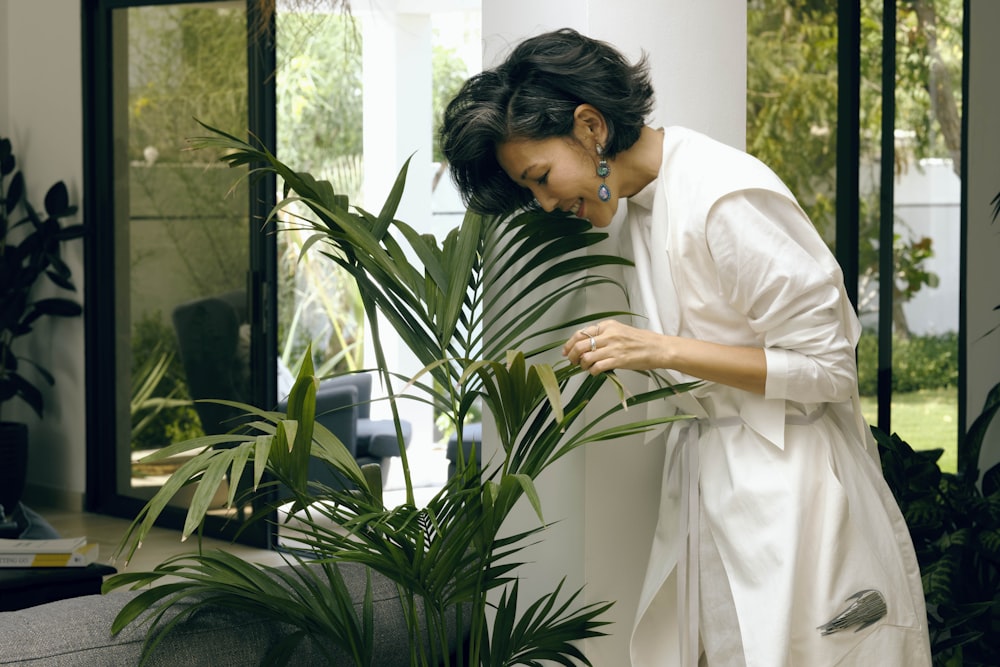 woman in white robe holding green plant