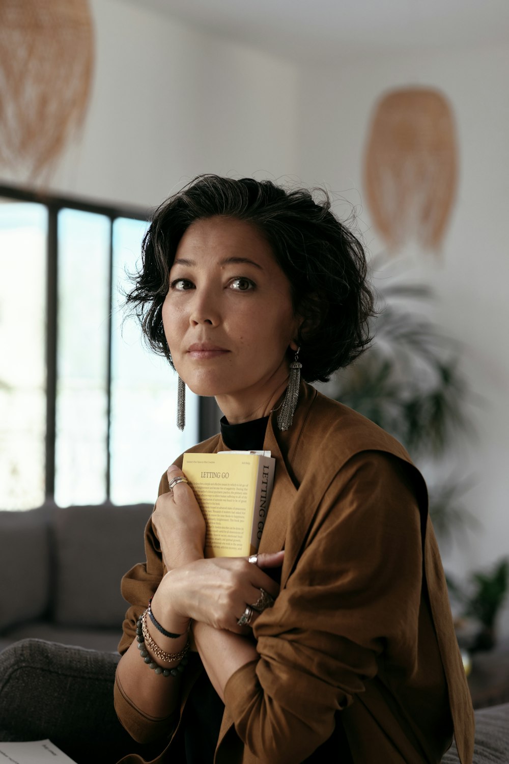 Mujer con abrigo marrón sosteniendo un libro amarillo