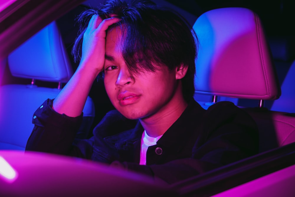 man in black jacket sitting on car seat